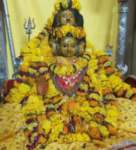 यह एक हिंदू देवता, संभवतः भगवान दत्तात्रेय की मूर्ति की तस्वीर है, जिसमें उनके तीन चेहरे दिखाई दे रहे हैं। मूर्ति को पूरी तरह से पीले और नारंगी गेंदे के फूलों की मालाओं से सजाया गया है। भगवान का दाहिना हाथ 'आशीर्वाद मुद्रा' में है। पृष्ठभूमि में पीले रंग का कपड़ा है और बगल में एक चांदी का त्रिशूल दिखाई दे रहा है।