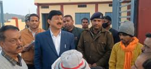 एक बाहरी स्थान पर वरिष्ठ अधिकारियों और पुलिसकर्मियों का समूह चर्चा कर रहा है। केंद्र में नीले रंग का ब्लेज़र और सफेद शर्ट पहने एक व्यक्ति कुछ बोल रहा है, जबकि उनके बगल में खाकी वर्दी और नीली टोपी पहने एक पुलिस अधिकारी खड़ा है। दाईं ओर नारंगी रंग का मफलर पहने एक अन्य व्यक्ति भी मौजूद है। यह दृश्य किसी आधिकारिक दौरे या जांच का प्रतीत होता है।